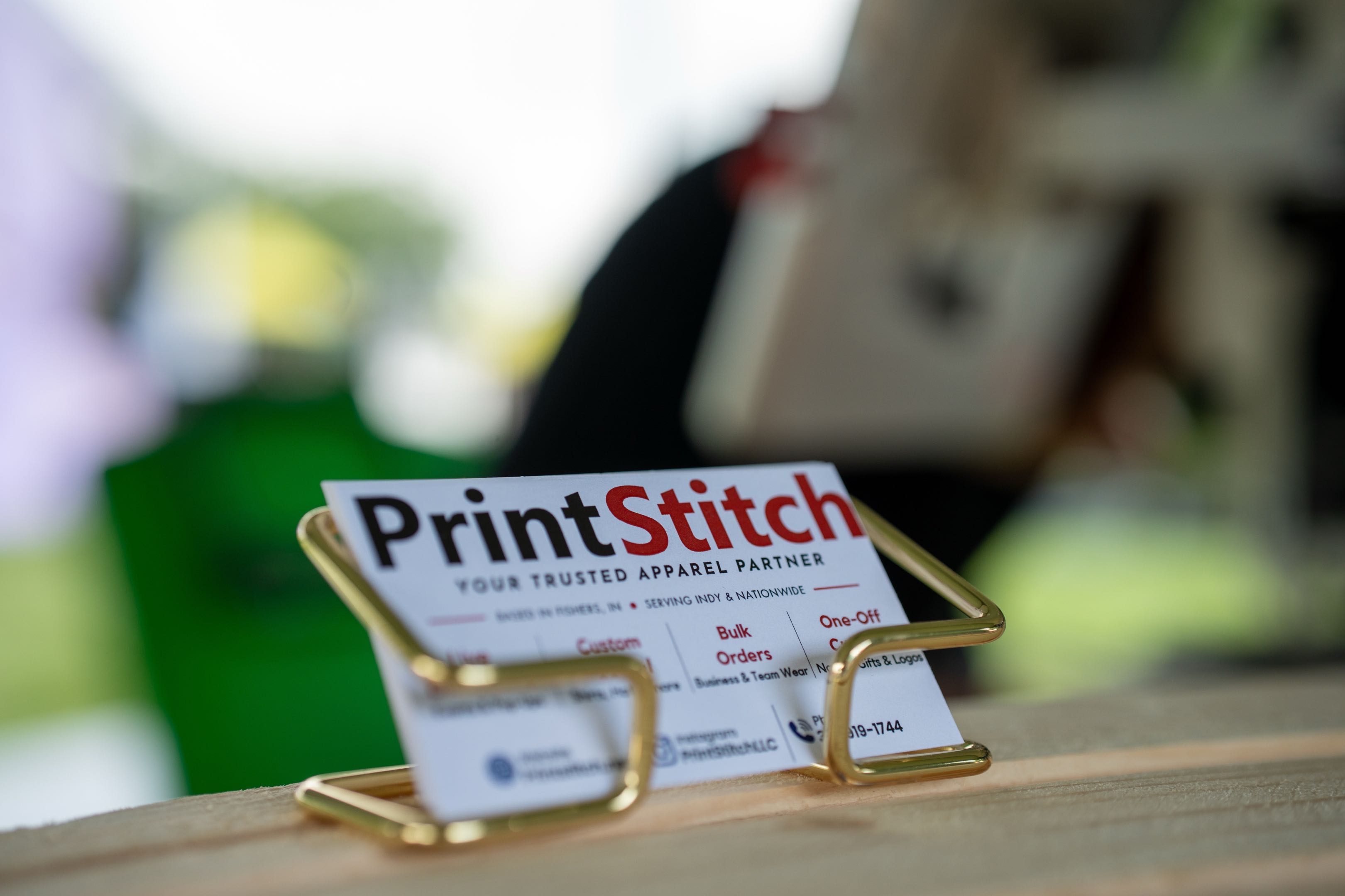 A PrintStitch business card on the table at a live embroidery event