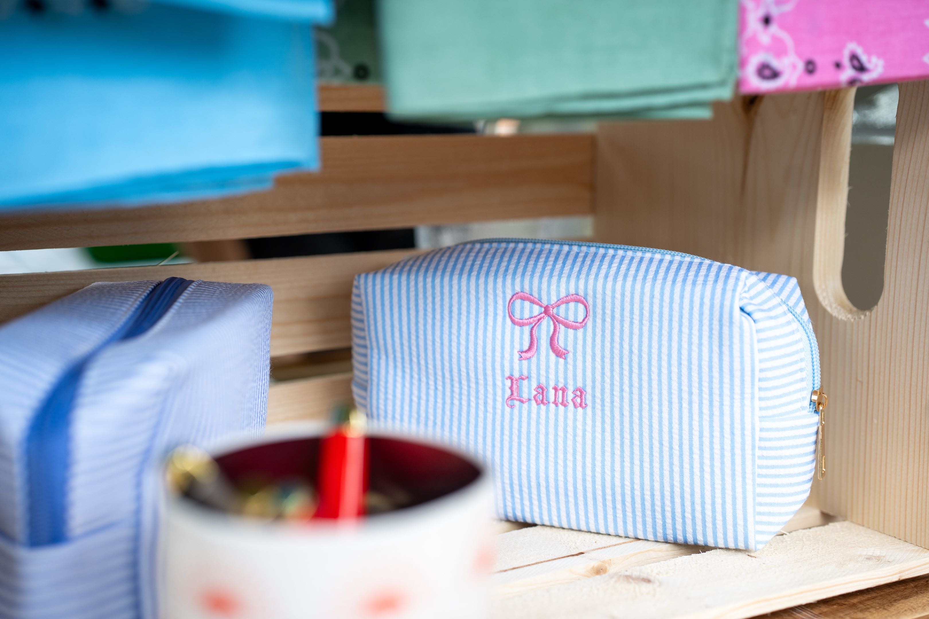 A seersucker pouch monogrammed with a name and a bow, embroidered on the spot at a live event