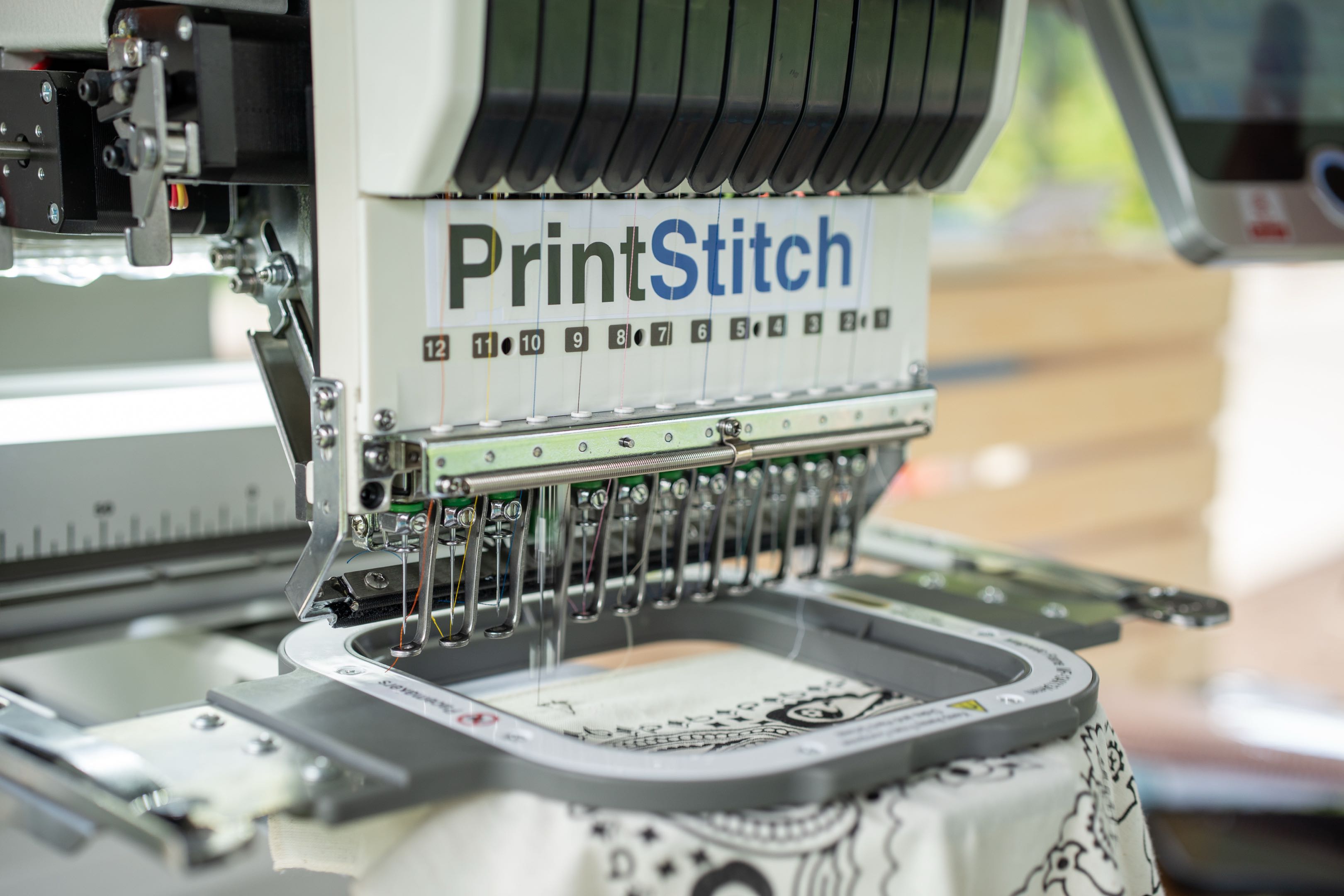 The PrintStitch twelve-needle embroidery machine stitching a custom bandana live — the same setup we bring to events in Bloomington, Indiana